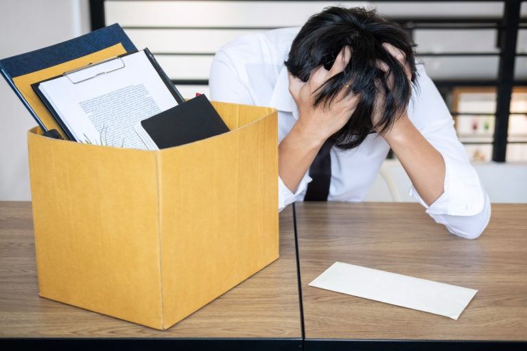 Demissão em período de estabilidade - homem com as mãos na cabeça ao lado de uma caixa com documentos